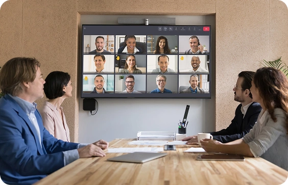 Sala de reuniones equipada con una pantalla que muestra a los participantes en una videoconferencia Tixeo