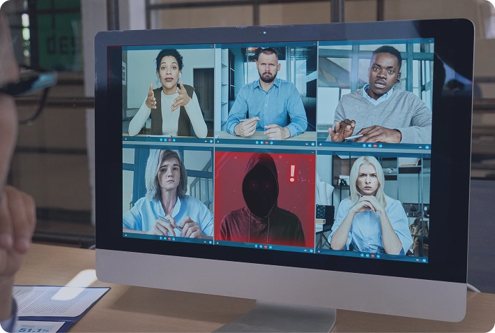 Pantalla de ordenador con una videoconferencia interrumpida por un intruso enmascarado
